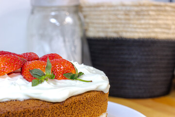 Cream tart with strawberries and lemon sponge cake on white plate