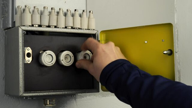 Replace a ceramic fuse in old fuse box. An open fuse box where an older ceramic fuse is screwed in where one is missing. An electrically hazardous light flash is visible when the fuse is screwed in. A