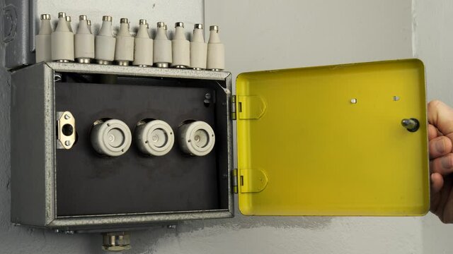 Open a old fuse box with three ceramic fuses. A metallic cabinet opens and behind it are older ceramic fuses. On top of the cabinet is a row of fuses. A homeowner intends to replace an electrical fuse