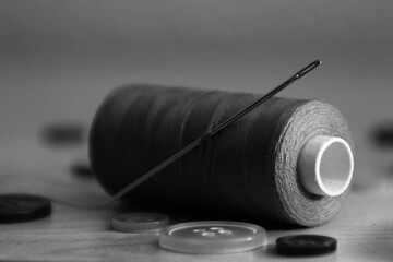 ein faden mit einer nadel in schwarz und weiß liegt auf dem tisch mit mehreren knöpfen, die nicht...