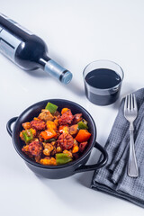 Extremadura crumbs, breadcrumbs, sausage, bacon, red and green peppers, garlic and paprika, with a glass of wine. Concept of traditional home cooking. Vertical photo and selective focus