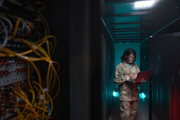 Portrait of young African-American woman wearing military uniform using laptop while standing in...