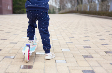 Little girl riding scooter in the park