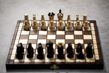 Wooden Chess pieces on board, arranged in incorrect initial position selective focus backlit. White...