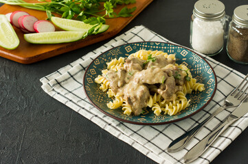 Italian whole grain pasta with roasted chicken liver and onions served on a plate on marble background
