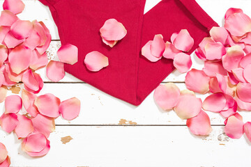 Red pants on white wood and some rose petals.The photo has a small space to put text.