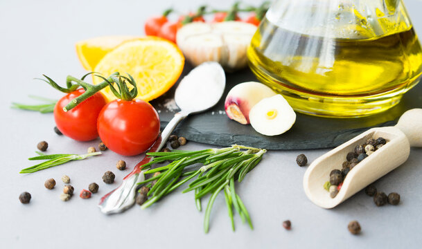A set of seasonings for cooking: olive oil, peppercorns, rosemary, salt, pepper, lemon. Image with selective focus