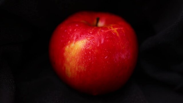 Red apple with water drops on black background