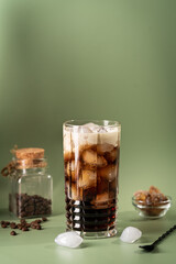 Glass with cold iced coffee and milk on green background