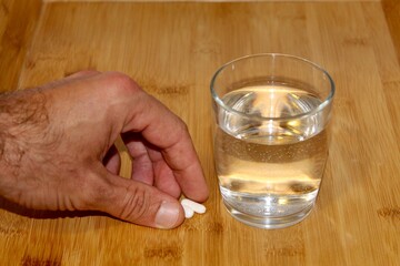 glass of water and hand taking two painkillers 