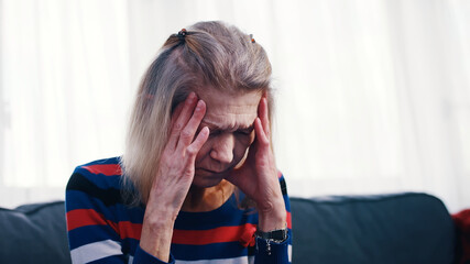 Elderly woman having a headache. Massaging temples. High quality photo