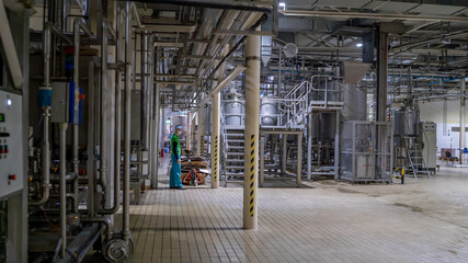 Looking on the giant industrial constructions on a food factory. An worker with cart goes in a far