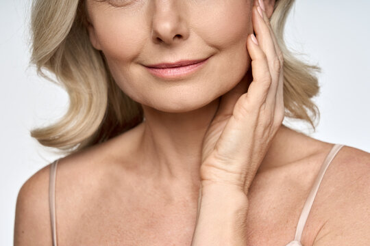 Face close up portrait of happy mid age 50 years old woman touching face with hand. Advertising of skin care anti wrinkle products for facial bottom part, lips, chin neck and decollete.