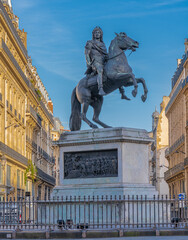 Paris, France - 03 28 2021: Vie of the Victories Square and statue of Louis XIV carrying his head in his hands at sunset