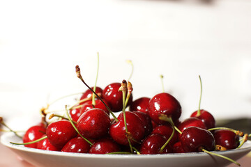 Plate with ripe red cherries on a white background