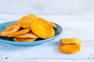 Healthy vegetarian sweets. Dried peaches on a blue plate on white wooden table