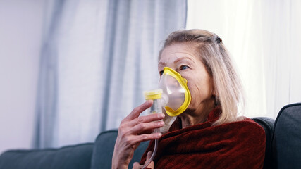 Vulnerable old woman in quarantine using oxygen inhaler and changing chanels on tv. High quality...