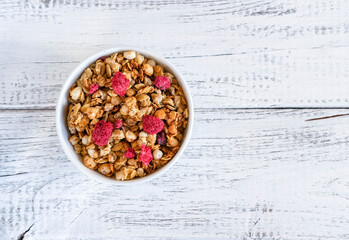 Healthy breakfast on wooden background. Bowl of muesli with dried raspberries