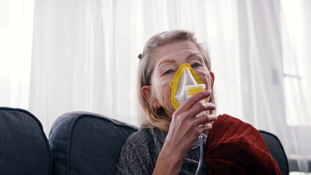 Older Woman Using A Respiratory Mask Inhaling Medicine To Clear Out Her Throat And Sinuses. High Quality Photo