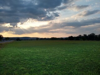 Summer Sunset with cloudy sky and green fields