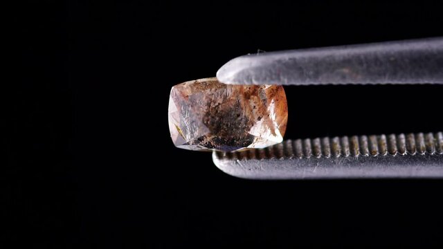 natural anadalusite in the tweezers on the background