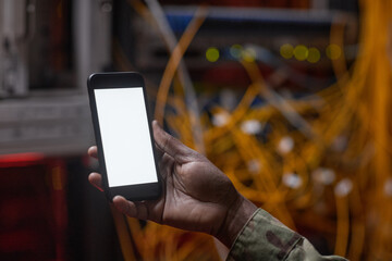 Close up of unrecognizable African-American woman holding smartphone with blank screen while inspecting server, copy space