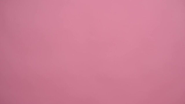 Hand shows the sign of peace and victory on a pink background