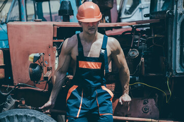 Fototapeta na wymiar Tired worker concept. Muscular builder with hard had. Sexy man with nude torso rest near construction equipment or tractor on background.