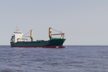 Floating green cargo ship at sea