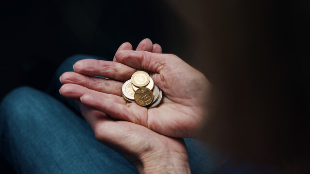 Wrinkled hands of elderly woman counting coins. Close up. High quality photo
