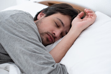 Young man sleeping peacefully lying in bed