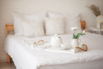 Cozy bedroom in light colors. Flowers, breakfast in bed.