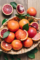 Whole and sliced blood oranges in a basket on wooden table background. Close up, flat lay