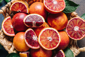 Whole and sliced blood oranges in a basket on blue table background. Close up - Powered by Adobe