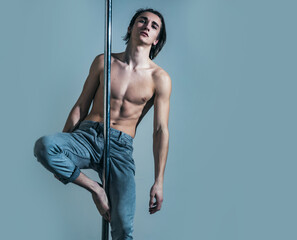 Attractive, sexy man performing pole dancing moves, work out, show trick. Guy makes figure on pole.