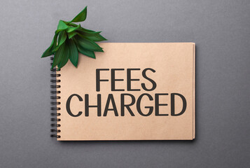 fees charged text on craft colored notepad and green plant on the dark background