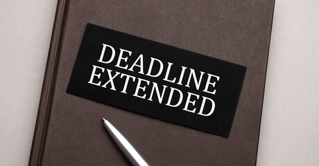 deadline extended sign written on the black sticker on the brown notepad. Tax concept