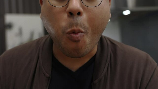 A young Asian man eating breakfast, he eats pork sausage. He poked it with a fork and bit his gut and chewed deliciously. Slow motion and movement short