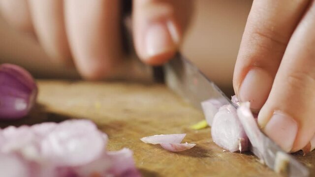 Chef chopping shallot on a wooden board. Close up. Preparing for cooking in Macro shot. Traditional thai ingredient.