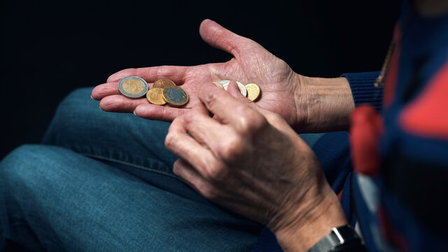 Old woman counting coins in her wrinkled hands. Close up. High quality photo