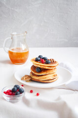 Freshly cooked delicious pancakes with honey, walnut, honey, raspberries and blueberries for breakfast.