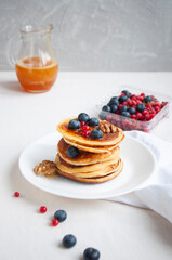 Freshly cooked delicious pancakes with honey, walnut, honey, raspberries and blueberries for breakfast.