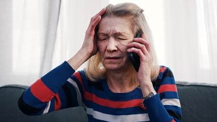 Desperate old woman having phone conversation with tears. High quality photo