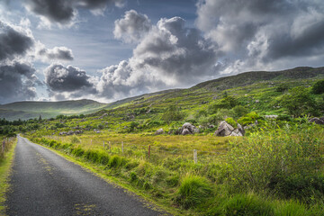 Straight country road leading trough valley, a rough landscape with rocky hills of Molls Gap in MacGillycuddys Reeks mountains, Ring of Kerry, Ireland