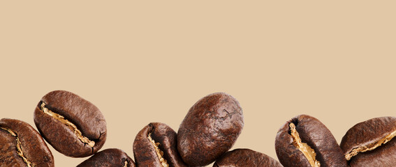 Freshly roasted Coffee Beans close-up on an isolated beige background. Banner with a place for the text.