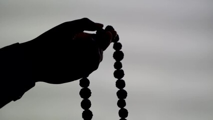 Silhouette clip of Prayer beads in hand. Male hand holding rosary, praying to god on white background, religious spirituality. Man holding rosary beads and meditating. Religious concept