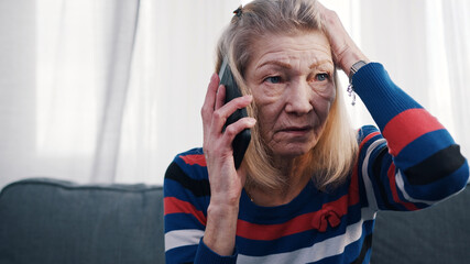 Elderly woman using smartphone to make phone call. Receiving bad news. High quality photo