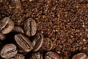 Brown roast, Dark roasts beans coffee on the texture of brown aromatic ground coffee. Macro view background with copyspace.