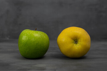 Two 2 different color apples, green and yellow on grey concrete background. Healthy life concept.