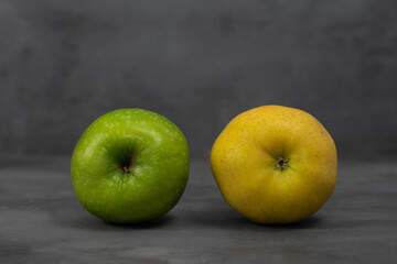 Two 2 different color apples, green and yellow on grey concrete background. Healthy life concept.